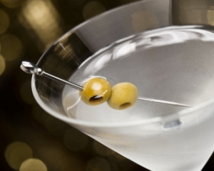 Vodka Martini with olive garnish in front of a gold glitter background