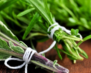 Bunches of assorted fresh herbs close up on wooden cutting board